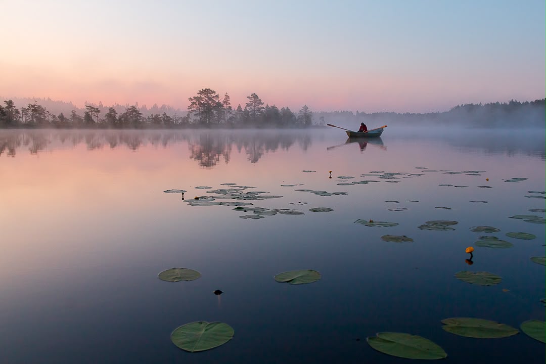 Dimmig sjö i soluppgång med roddbåt, fotograferad av Margareta Sarvela